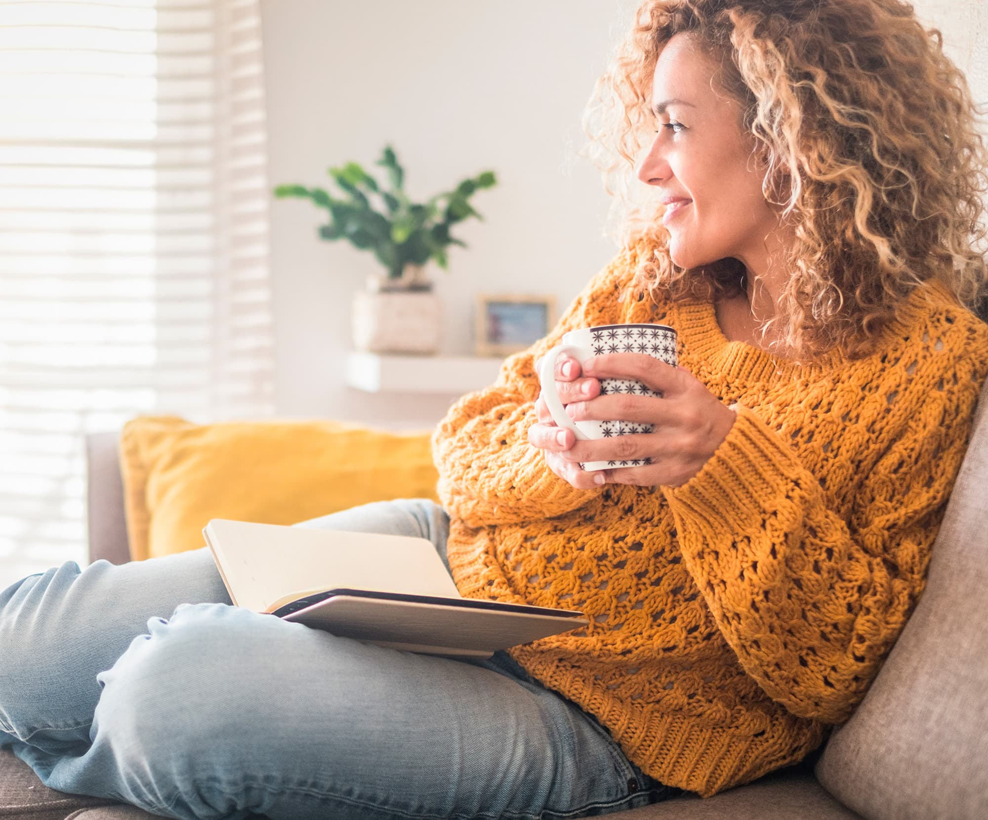 Apartment available for woman in yellow sweater reading holding a coffee mug